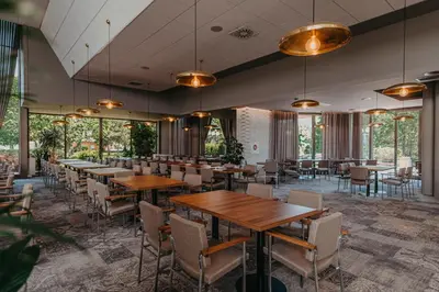 a restaurant with wooden tables and chairs and windows at Happy Camp Mobile Homes in Camping Terme Čatež in Čatež ob Savi