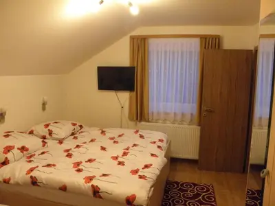 a bedroom with a bed with red flowers on it at Hotel and Restaurant Ana in Hrib-Loški Potok