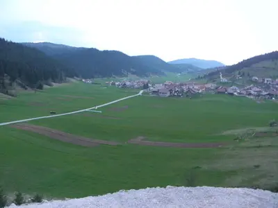 a large green field with a town in the distance at Hotel and Restaurant Ana in Hrib-Loški Potok