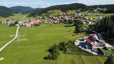 an aerial view of a village in a green field at Hotel and Restaurant Ana in Hrib-Loški Potok