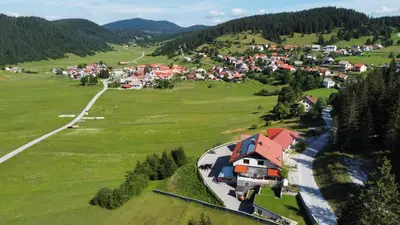 an aerial view of a village in a green field at Hotel and Restaurant Ana in Hrib-Loški Potok