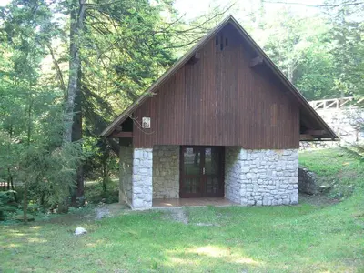 a small stone and wood building in the grass at Camping Pivka Jama Postojna in Postojna