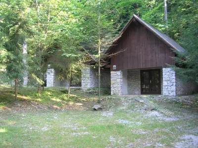 a small stone house in the middle of a forest at Camping Pivka Jama Postojna in Postojna