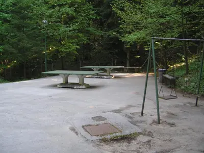 two picnic tables in a parking lot with trees at Camping Pivka Jama Postojna in Postojna