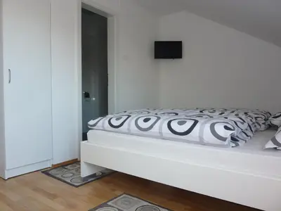 a white bed with a black and white comforter at Rooms Mira G in Postojna