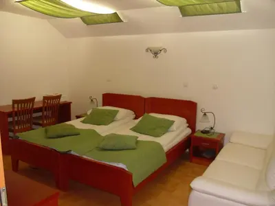 a bedroom with a bed with green pillows and a couch at Gostilna in prenočišče KOCJAN in Bizeljsko