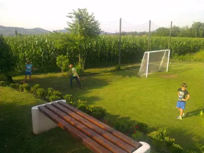 two children playing soccer in a field with a bench at Gostilna in prenočišče KOCJAN in Bizeljsko