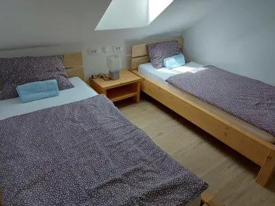 a bedroom with two beds and a night stand at Apartma Markelj in Radovljica