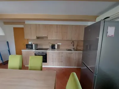 a kitchen with wooden cabinets and green chairs and a refrigerator at Apartma Markelj in Radovljica