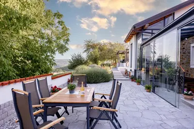an outdoor patio with a wooden table and chairs at Sunny Hill in Vremski Britof