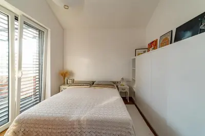 a white bedroom with a bed and a window at Sunny Hill in Vremski Britof