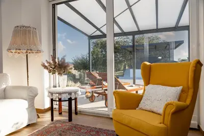a living room with a yellow chair and sliding glass doors at Sunny Hill in Vremski Britof