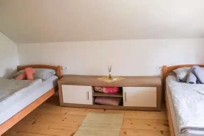 a room with two beds and a wooden table at ABC Apartma Kočevsko in Kočevje