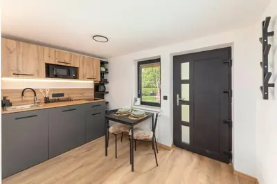 a kitchen with a table and a black door at Naša hiša in Bohinj