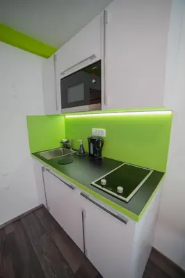 a green and white kitchen with a sink and a microwave at Naša hiša in Bohinj