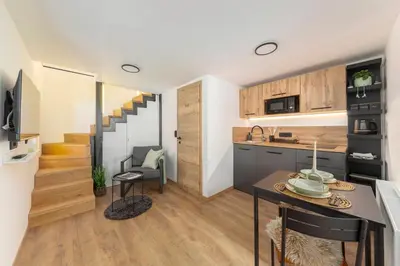 a kitchen and living room with a table and a staircase at Naša hiša in Bohinj