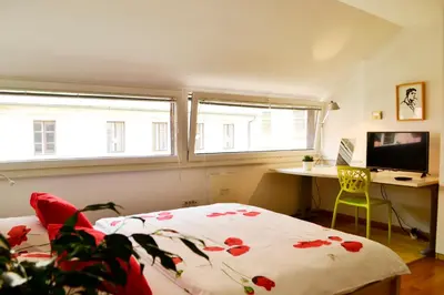 a bedroom with a bed and a desk and two windows at Studio in Ljubljana Center in Ljubljana