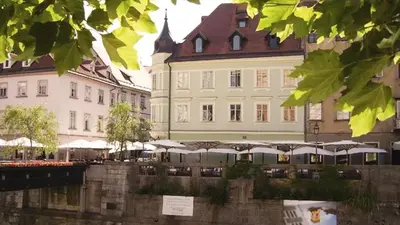 a large building with tables and umbrellas in front of it at Studio Emmi in Ljubljana