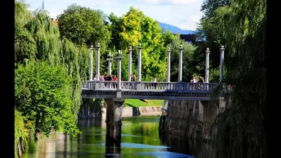 a bridge over a river with people walking on it at Bright Apartment in Ljubljana