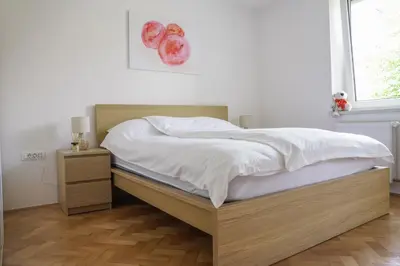 a bedroom with a bed with a wooden frame and a window at Bright Apartment in Ljubljana