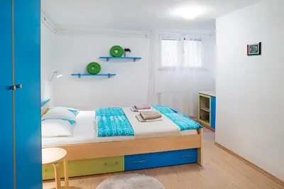 a small bedroom with a bed and two shelves on the wall at Apartments Your Colourful Ljubljana Home in Ljubljana