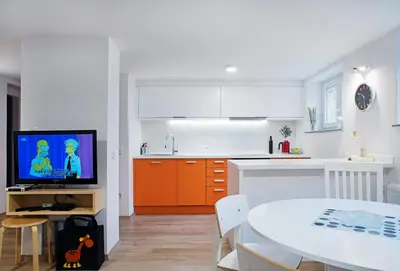 a kitchen with a table and a tv in a room at Apartments Your Colourful Ljubljana Home in Ljubljana