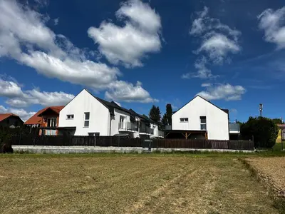 two white houses with a fence and a field at Apartma Rebolj in Moravske Toplice
