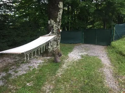 a hammock hanging from a tree in a yard at Vilijev Raj, a property with cottage in the countryside in Avče