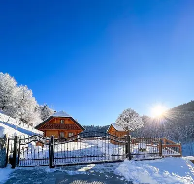 a fence in the snow in front of a house at Hiška Erika - Wood House Erika in Šoštanj