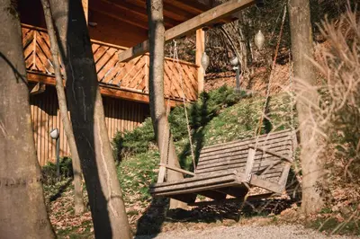 a wooden bench swing in front of a cabin at Hiska Na Samem v Slovenj Gradcu in Slovenj Gradec