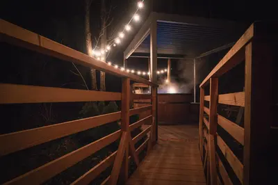 a porch with lights and a fence at night at Hiska Na Samem v Slovenj Gradcu in Slovenj Gradec