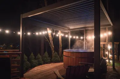 a pergola with a hot tub on a deck at night at Hiska Na Samem v Slovenj Gradcu in Slovenj Gradec