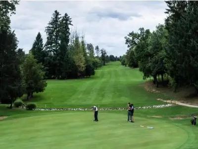 two people standing on a green golf course at Počitniška hišica Patrik Terme Čatež in Mostec
