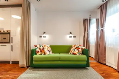 a green couch with pillows on it in a living room at SIX IN THE CITY Apartment, LJUBLJANA in Ljubljana