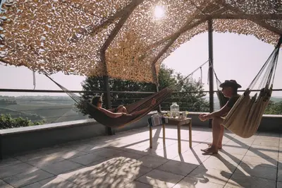 two people are sitting in hammocks on a balcony at Holiday house Podhamer Marijan in Ljutomer