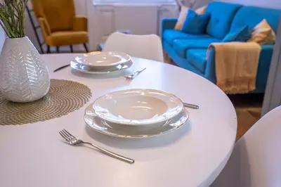 a white table with plates and silverware on it at Downtown Luxury Retreat in Ljubljana