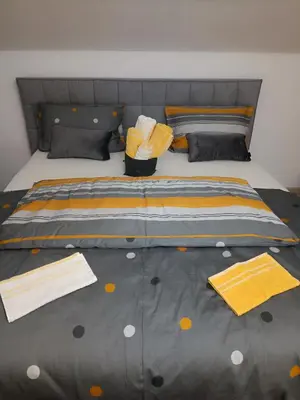 a bed with yellow and gray sheets and pillows at Vila Frigo Olimia in Podplat