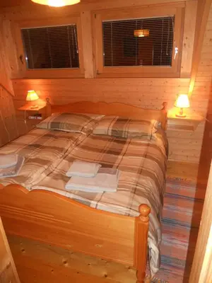 a bed in a wooden room with two lamps and two windows at Holiday Home Gobela in Kranjska Gora