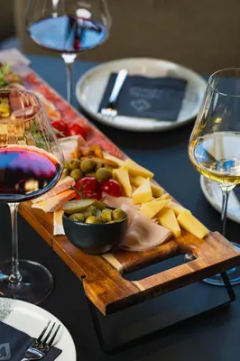 a table with a tray of cheese and a glass of wine at Hotel Lonca in Škofja Loka