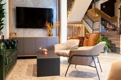 a living room with a couch and chairs and a tv at Hotel Lonca in Škofja Loka