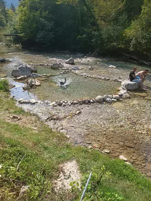 two people are sitting on rocks in a river at Riverside Guesthouse in Ig