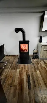 a black stove in a room with a wooden floor at Riverside Guesthouse in Ig