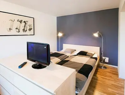 a bedroom with a bed with a desk with a television on it at Studio My Ljubljana Home in Ljubljana