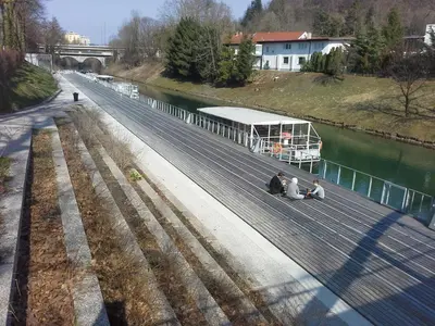 a group of people sitting on a dock next to a river at Studio My Ljubljana Home in Ljubljana