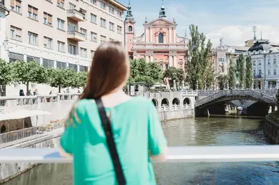 a woman looking over a river in a city at Romantic JUMP Studio overlooking river, free parking in Ljubljana