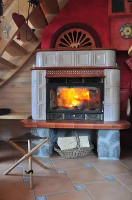 a fireplace in a living room with a stove at Chalet Alpinka in Cerklje na Gorenjskem