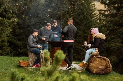 a group of people standing around a grill at Chalet Alpinka in Cerklje na Gorenjskem