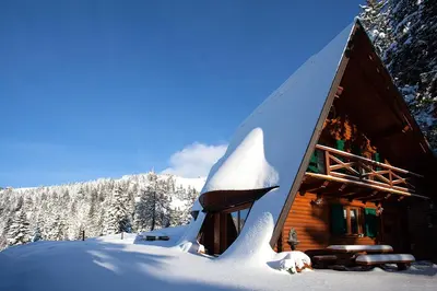 a snow covered log cabin with a snow covered roof at Chalet Alpinka in Cerklje na Gorenjskem