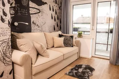 a living room with a white couch in front of a window at Ljubljana Urban Apartments - Quiet Stay & Free Parking in Ljubljana
