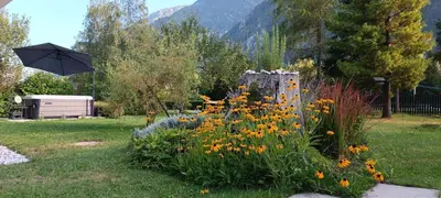 a garden with a bunch of flowers and an umbrella at House Apartma Čebela with jacuzzi in Gozd Martuljek